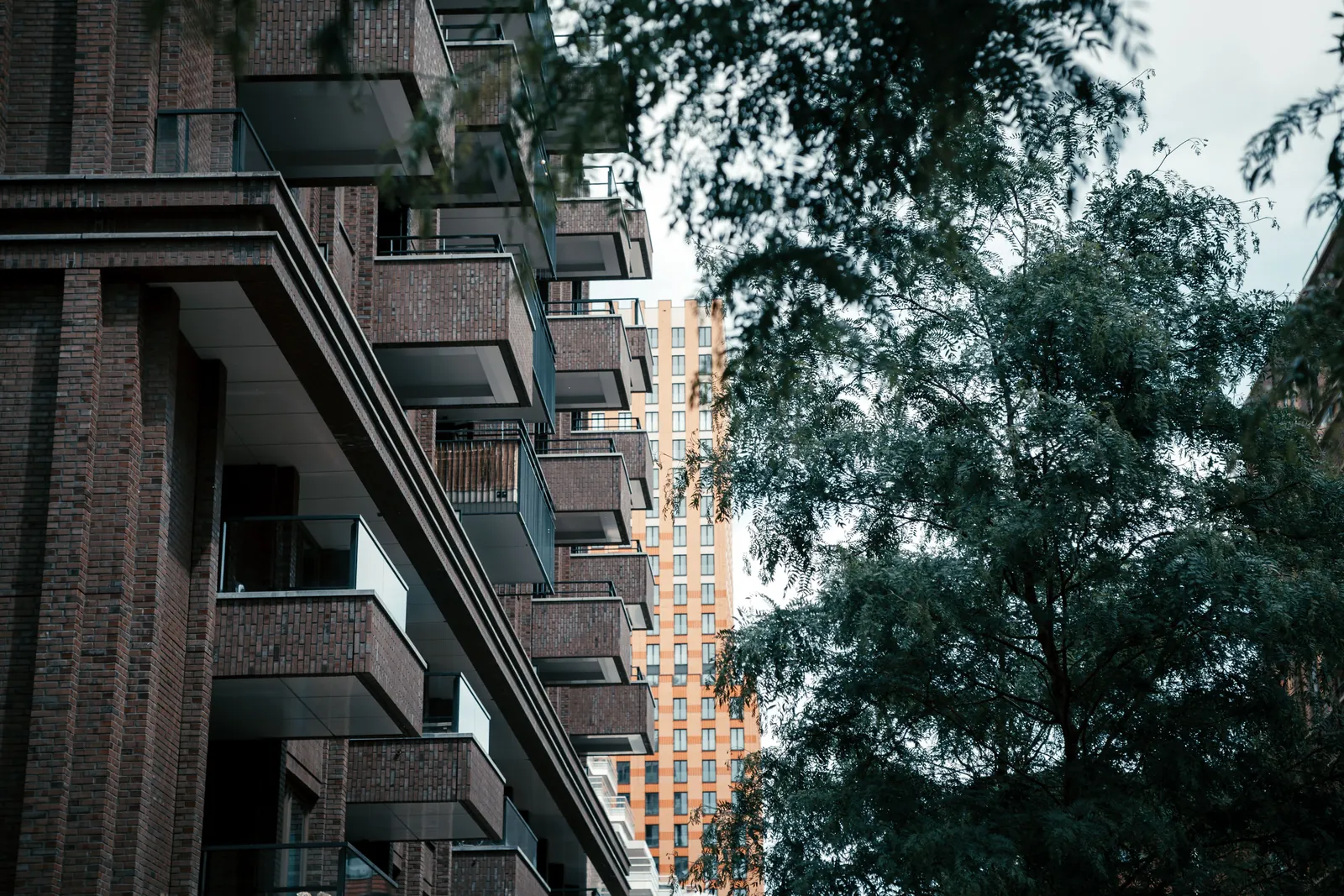 Edificio de ladrillo oscuro con balcones entre árboles